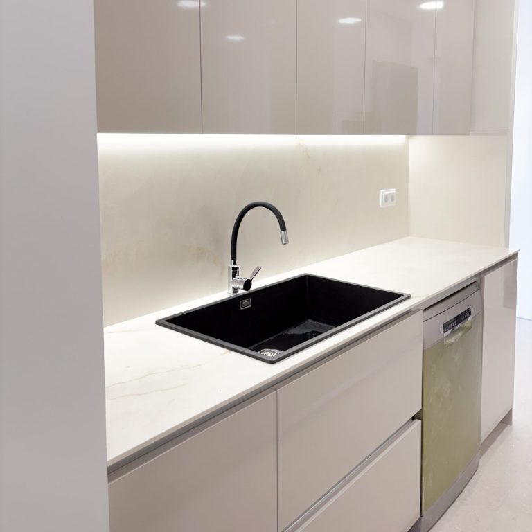 Reformas de cocinas Cocina moderna con encimera blanca, fogones negros y grifería de cobre.