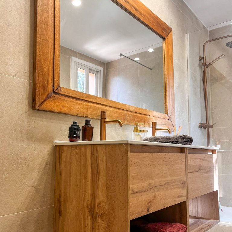 Reformas de baños Baño moderno con lavabo de mármol y espejo grande en un marco de madera.