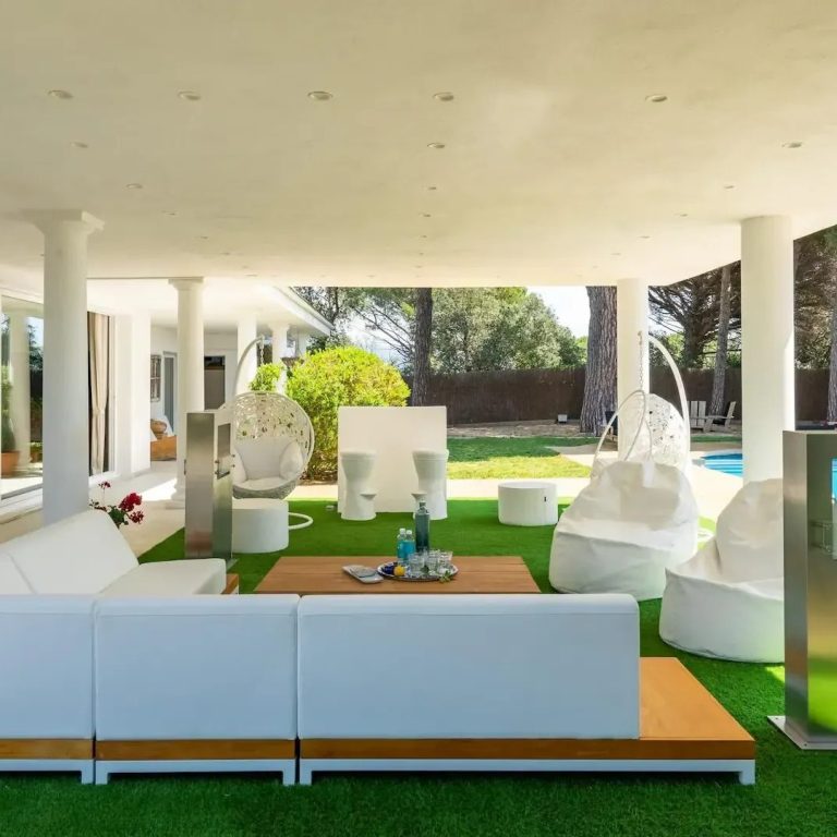 Reformas exteriores Zona de estar al aire libre con muebles blancos y césped verde.